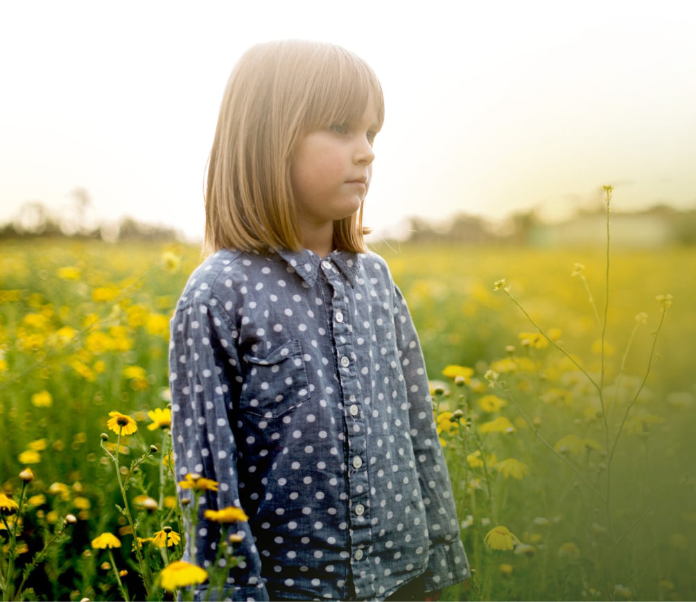 Child standing in a sunny flower field