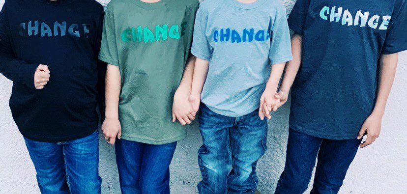 Children holding hands wearing change message shirts