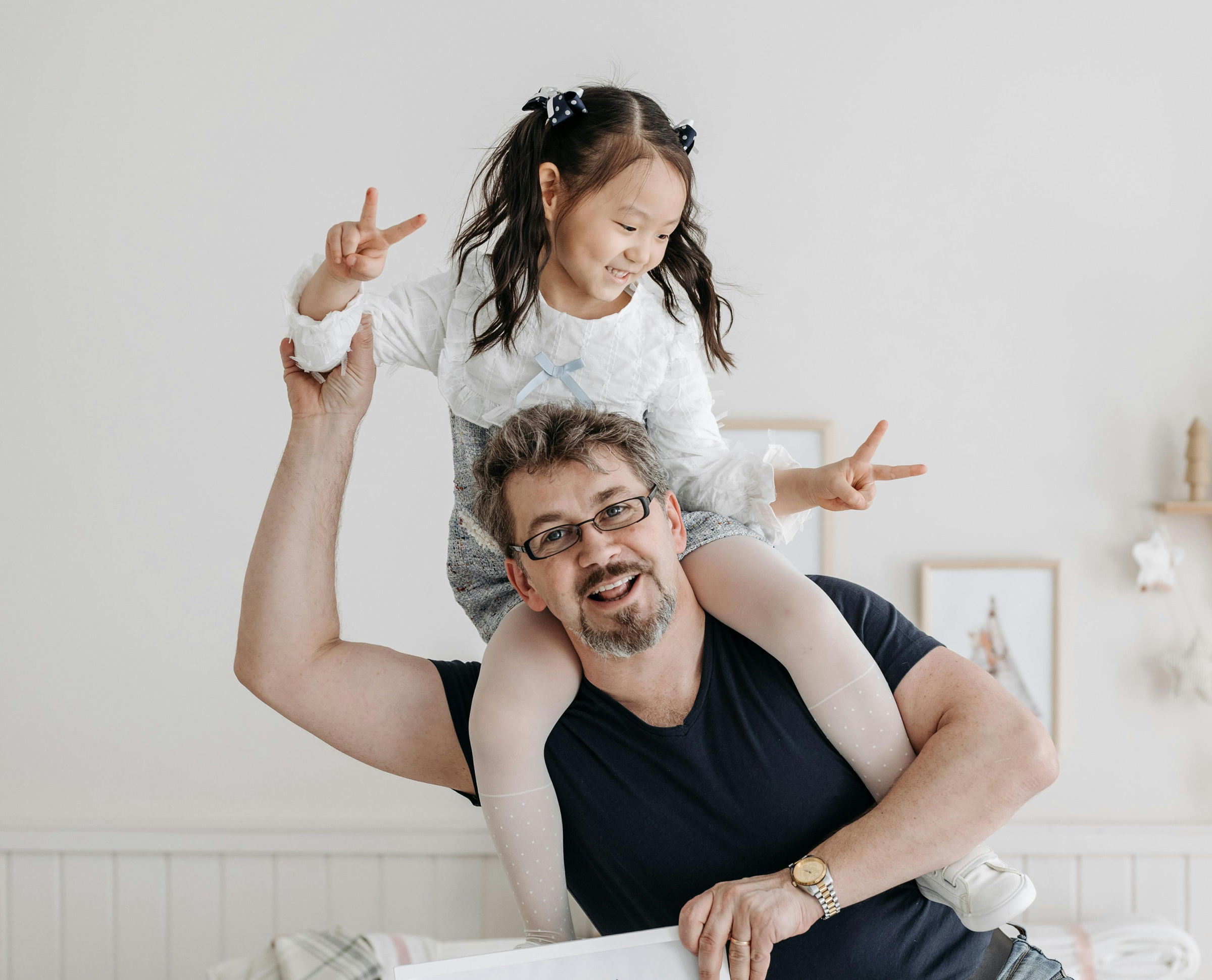 Smiling man carries happy girl on shoulders