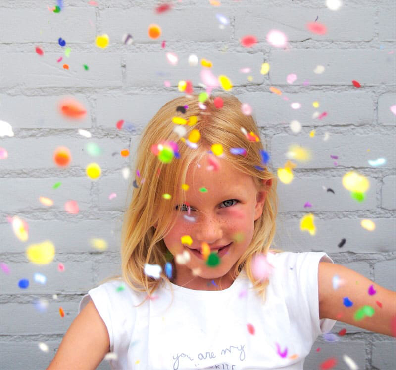 Smiling child surrounded by colorful confetti