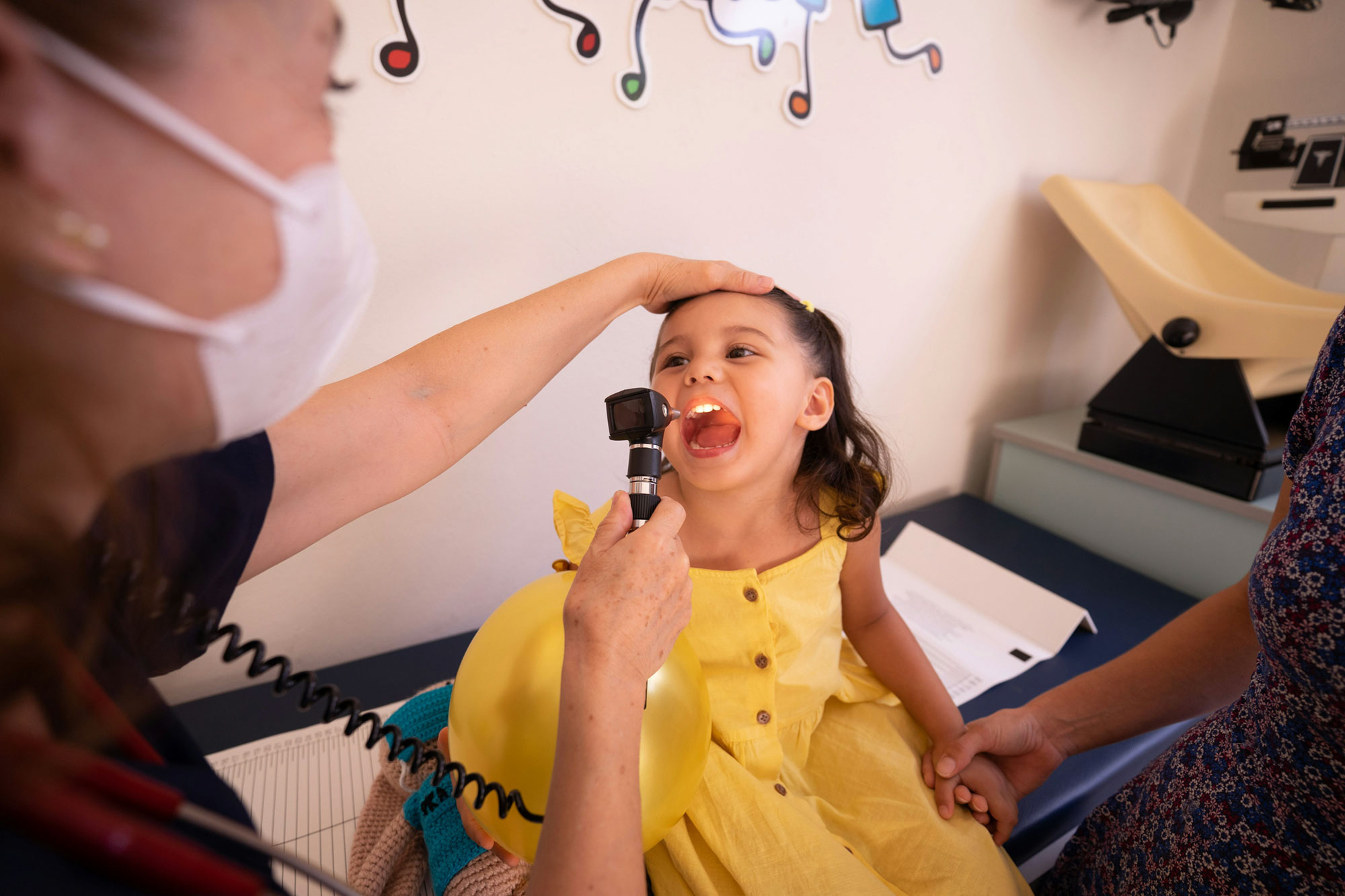 Doctor examining child's throat in clinic