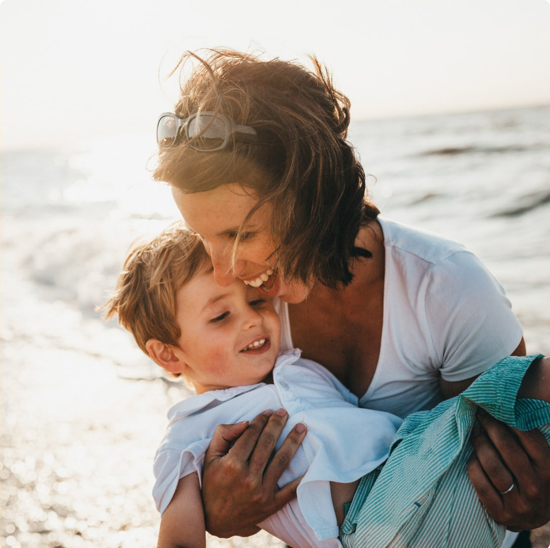 Mother holding child and smiling at beach