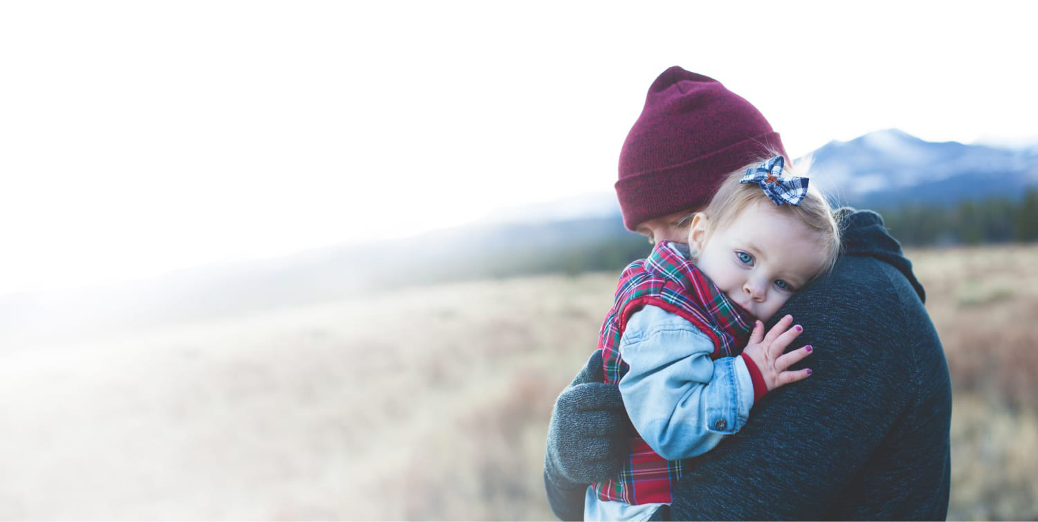 Parent holding baby outdoors in winter clothes