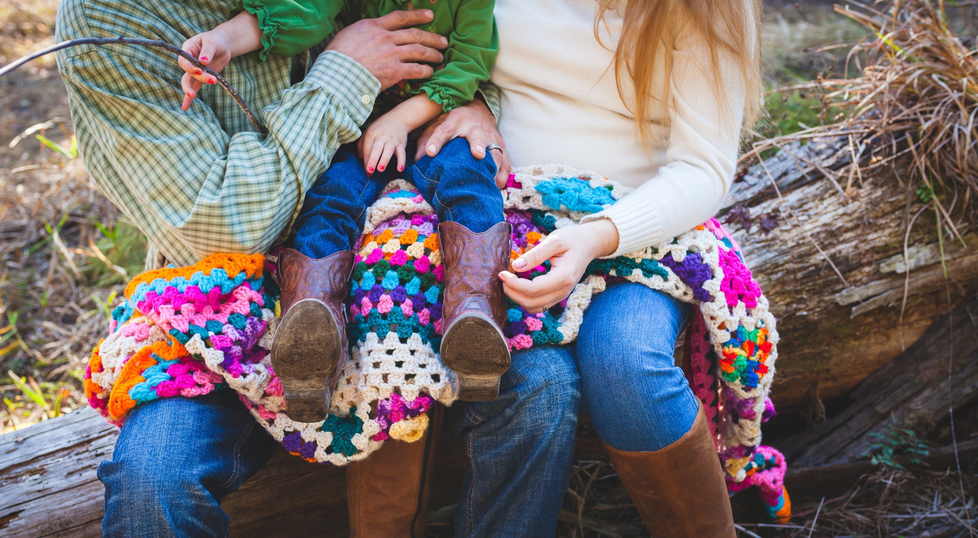 Family sitting outdoors with colorful crochet blanket